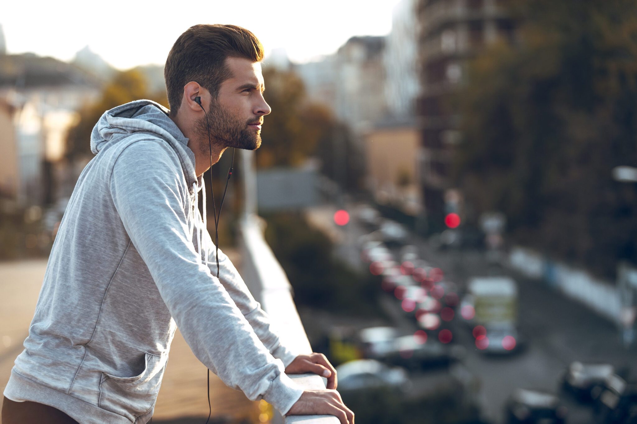 A man in a hoodie looking out over a city as he seeks support for cbt for depression.